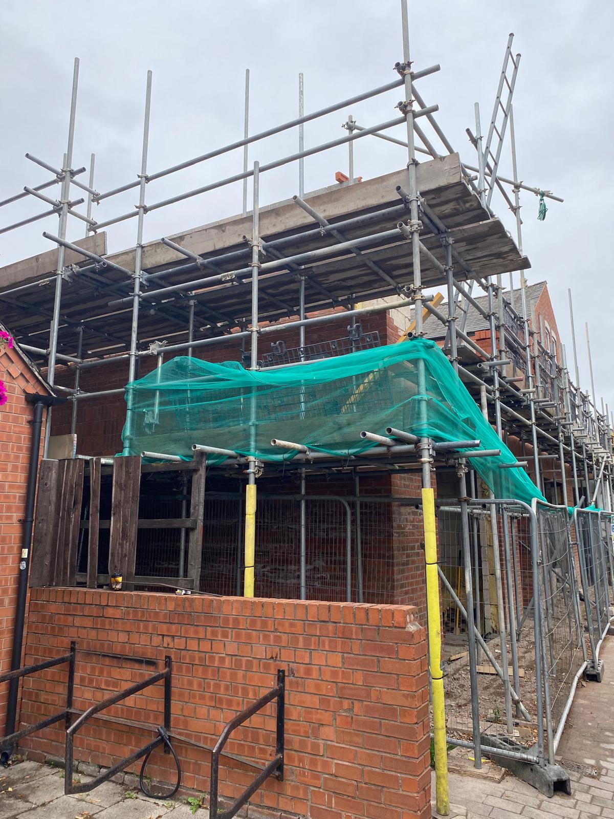 Front elevation scaffolded with debris netting in place.