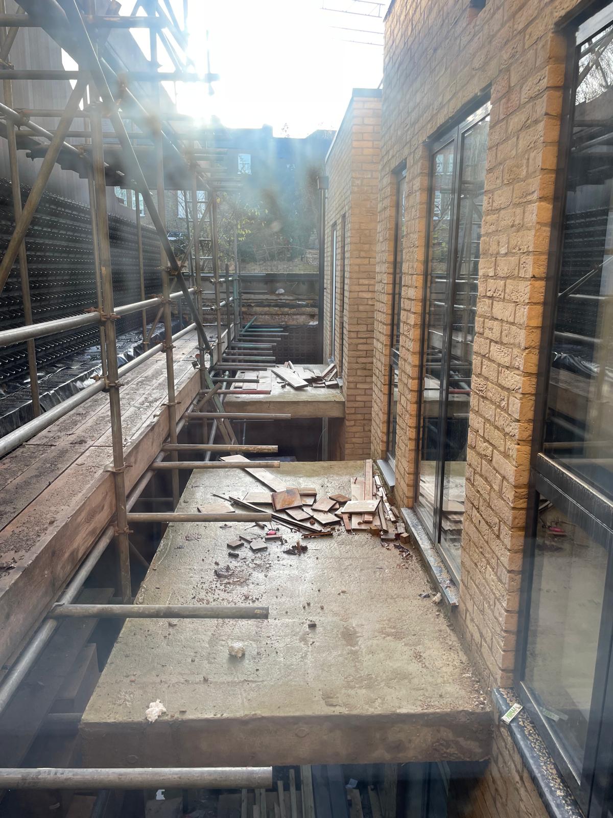 Rear elevation scaffolded, with new brickwork progressing.