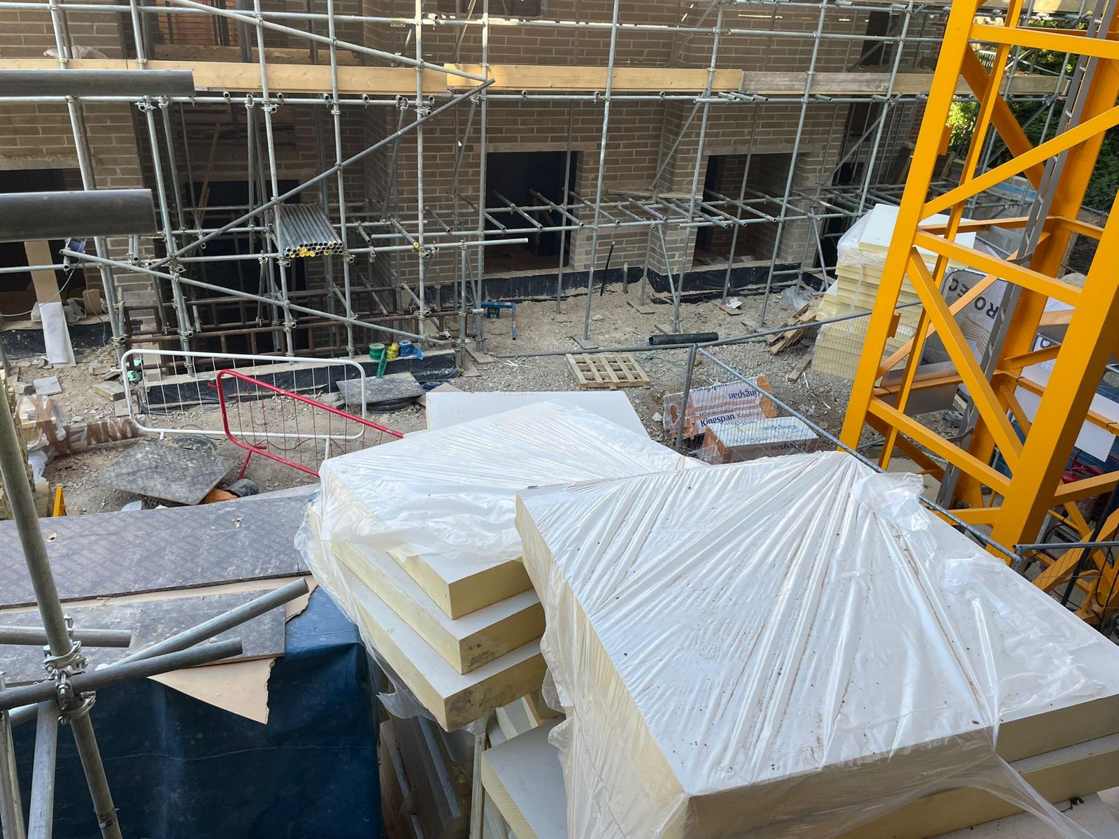 Insulation boards craned in and stored on the scaffold landing.