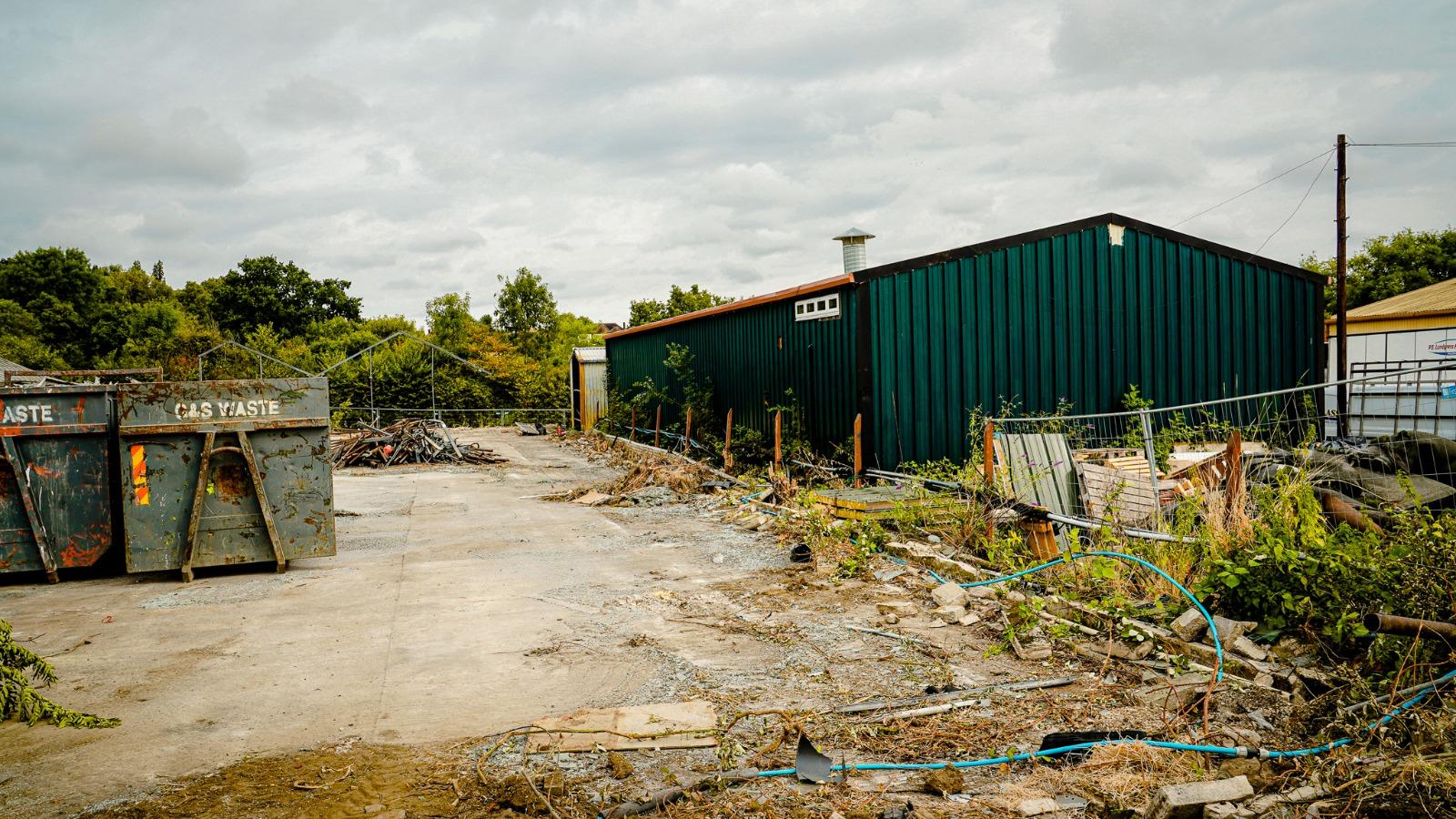 Clearance waste segregated into skips beside the former storage buildings.
