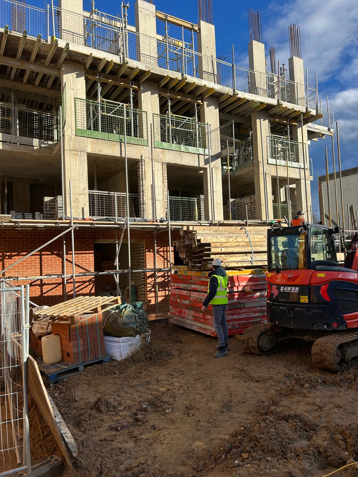 Masonry following the frame, with block and brick delivered into the working area.